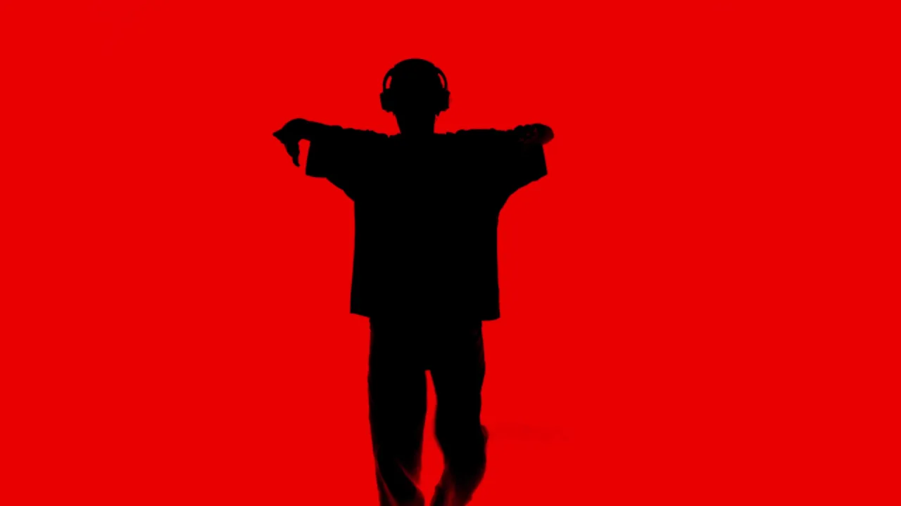 Black silhouette of a dancer against a saturated red background