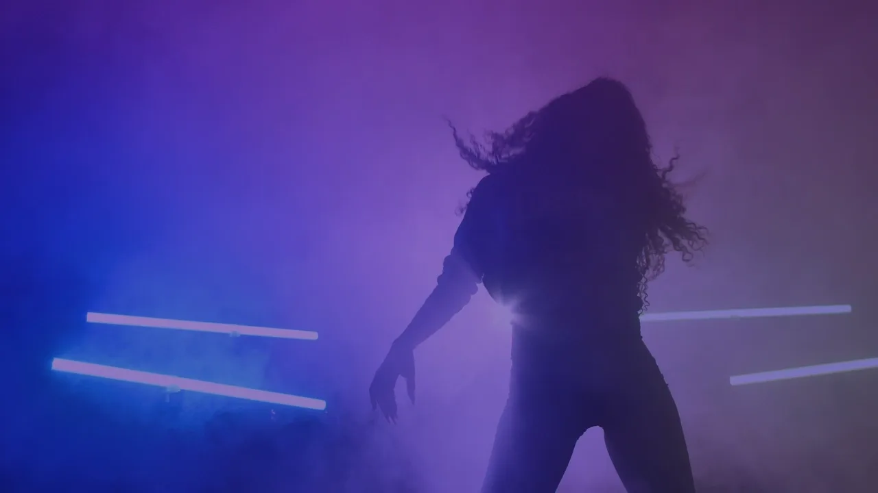 Silhouette of a dancer in purple haze with blue light bars