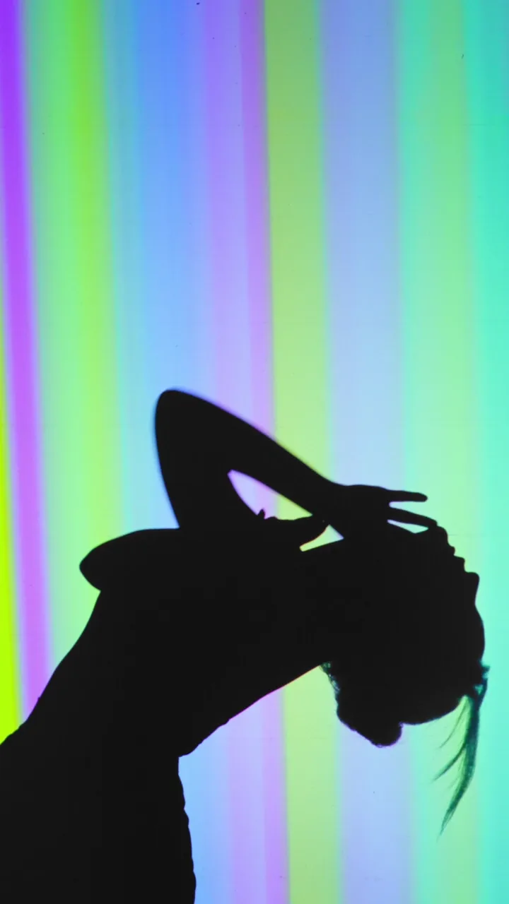 Silhouette of a dancer against vertical rainbow light