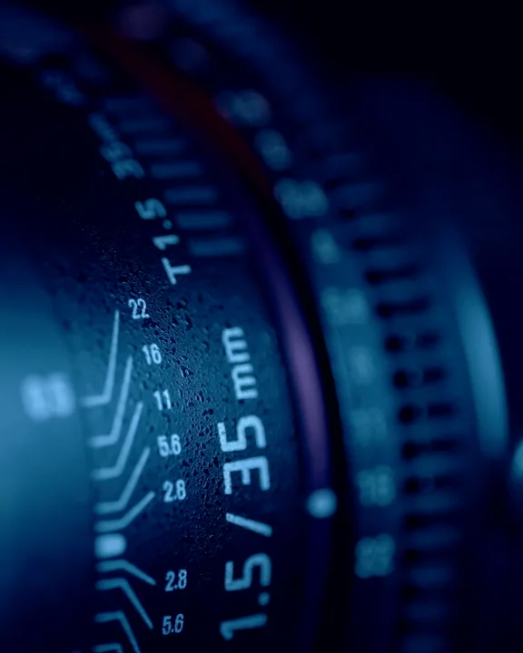 Close-up of a camera lens in cold blue light — portrait placeholder